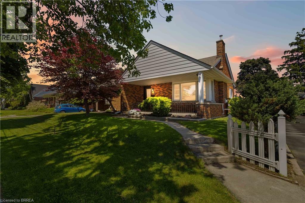 Brick exterior with white siding accents and a covered front porch featuring white pillars - 134 Queensway Drive, Brantford, ON