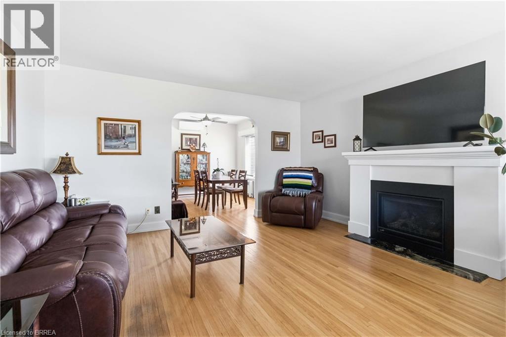 Hardwood flooring throughout a living space featuring a white mantel fireplace with a dark stone hearth - 134 Queensway Drive, Brantford, ON