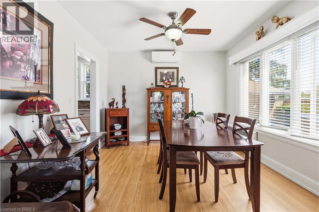 Dining area featuring light wood-finish flooring, a ceiling fan with integrated lighting, multiple windows with blinds, an air conditioning unit, and a doorway to another room - 134 Queensway Drive, Brantford, ON