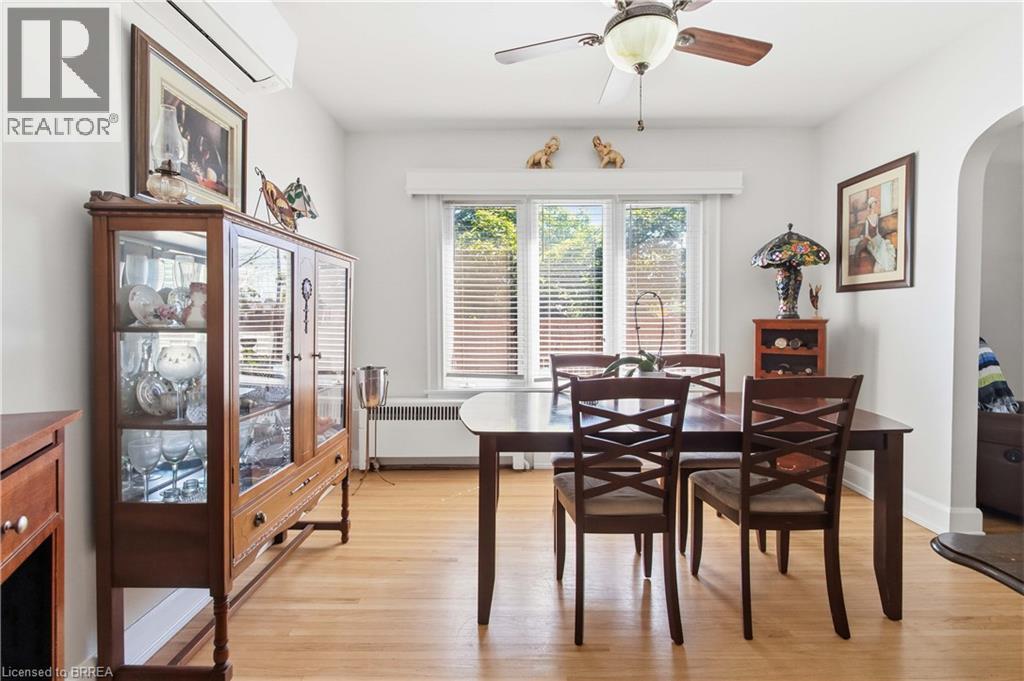 Bright interior space featuring light wood-finish flooring, a ceiling fan with integrated lighting, and multiple windows with blinds - 134 Queensway Drive, Brantford, ON
