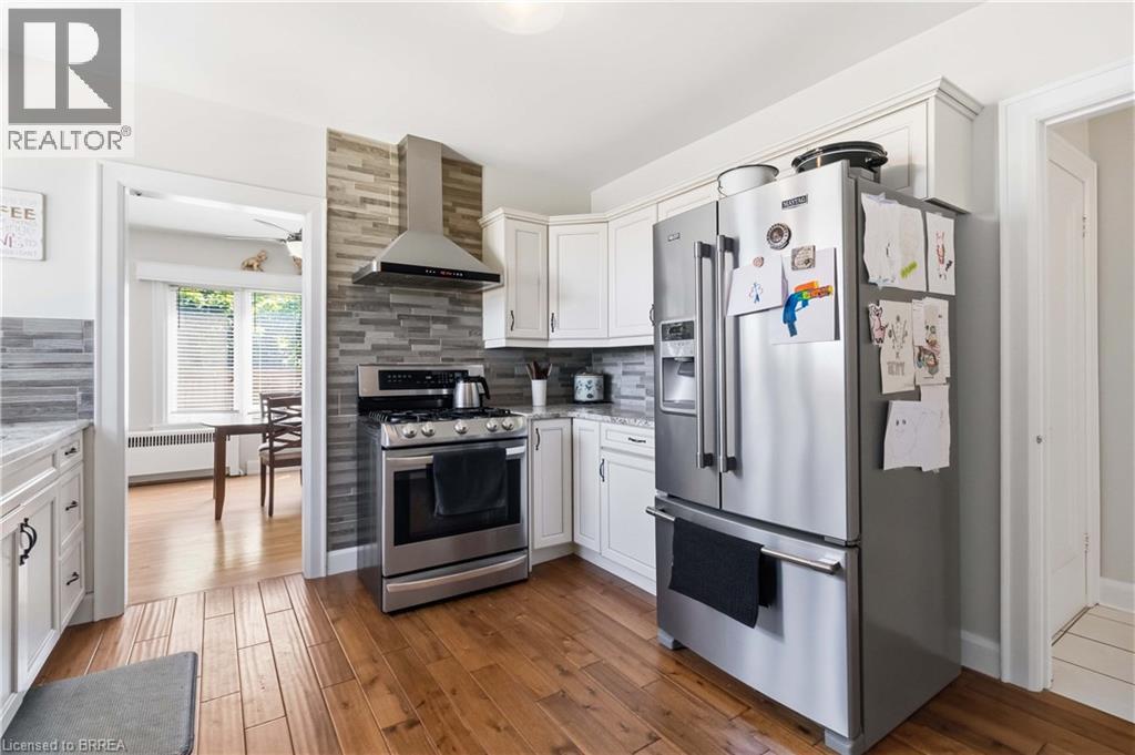 Kitchen featuring wood-finish flooring, white cabinetry, and stainless steel appliances - 134 Queensway Drive, Brantford, ON