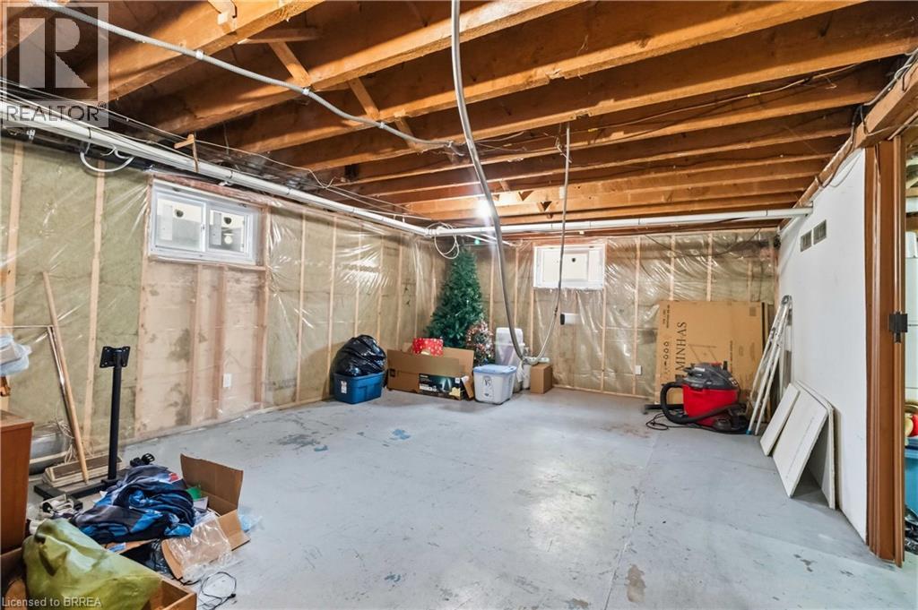 Unfinished basement space featuring exposed wood joists, concrete flooring, two windows, and an insulated wall with vapor barrier - 134 Queensway Drive, Brantford, ON