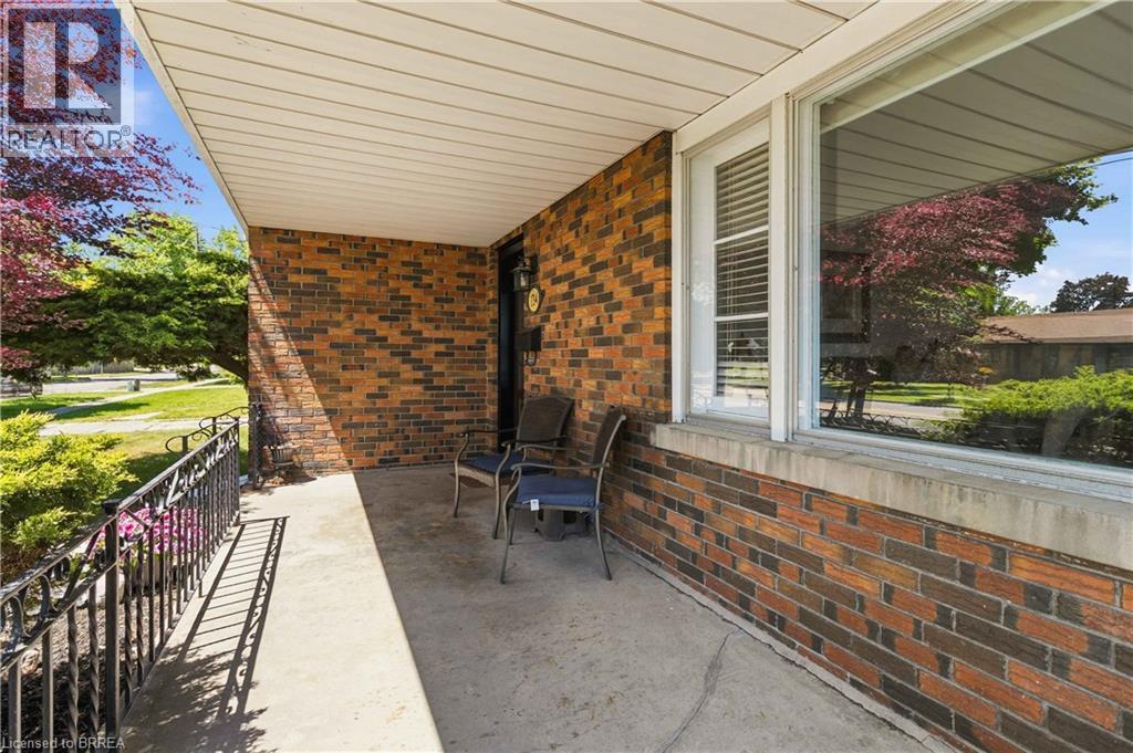 Covered concrete porch featuring brick veneer siding and a large picture window - 134 Queensway Drive, Brantford, ON