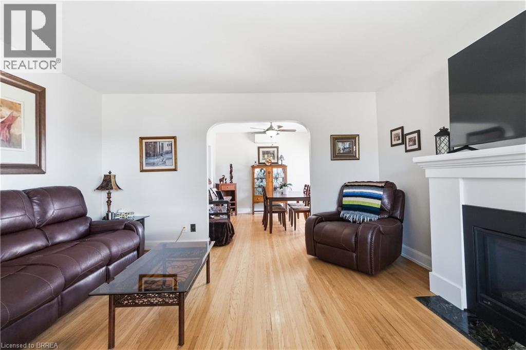 Hardwood flooring throughout, white walls, fireplace with white mantel and dark stone hearth, and an arched entryway - 134 Queensway Drive, Brantford, ON