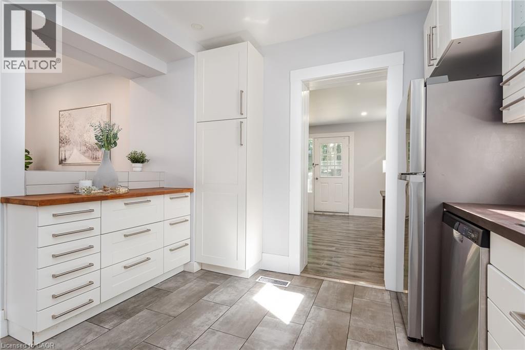 Contemporary kitchen featuring wood-finish countertops, subway tile backsplash, and light gray rectangular floor tiles - 40 Woodland Avenue, Kitchener, ON