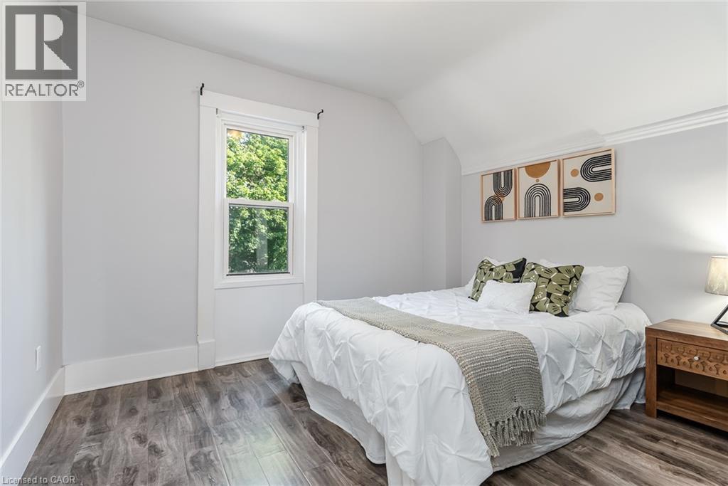 Bedroom featuring wood-finish flooring, a single window with white trim, and light gray wall paint - 40 Woodland Avenue, Kitchener, ON