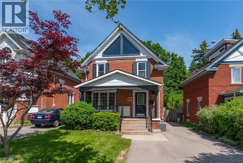 Bedroom featuring light gray walls, white trim, a large window, a five-panel interior door, and wood-finish flooring - 40 Woodland Avenue, Kitchener, ON