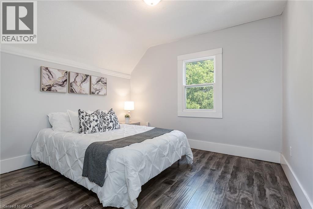 Spacious room featuring wood-finish flooring, crisp white baseboards, and a single-pane window - 40 Woodland Avenue, Kitchener, ON