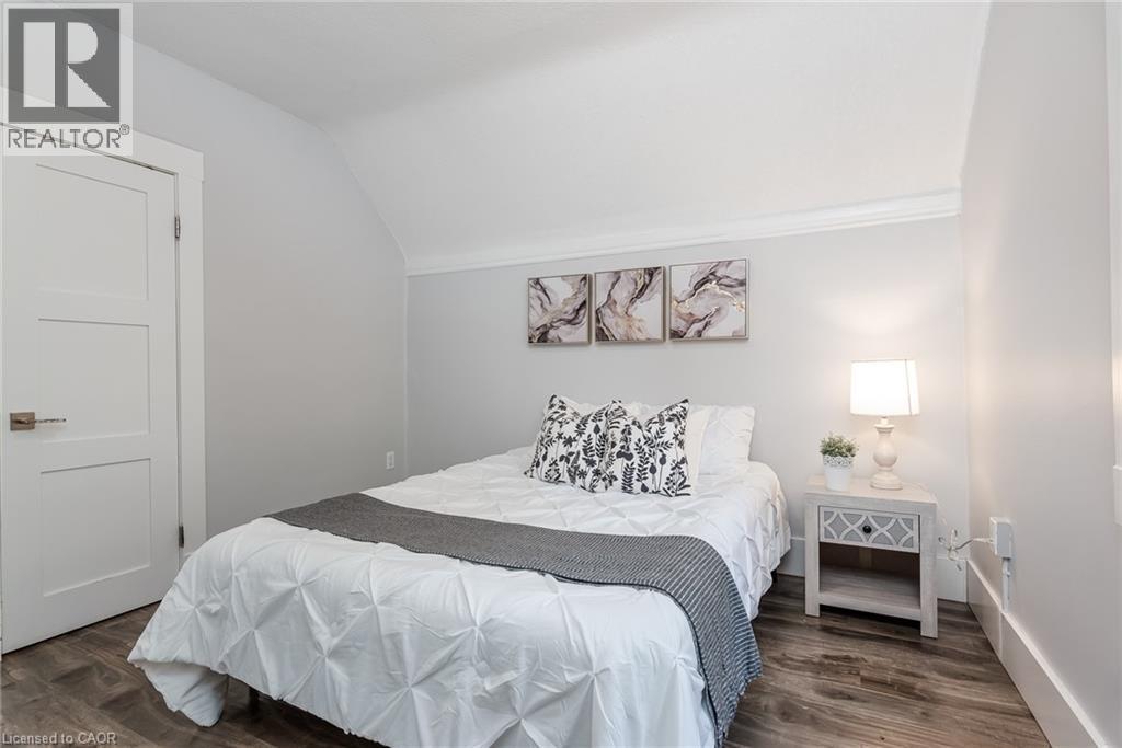 Room featuring wood-finish flooring, a three-panel interior door with brushed nickel hardware, and neutral wall tones - 40 Woodland Avenue, Kitchener, ON
