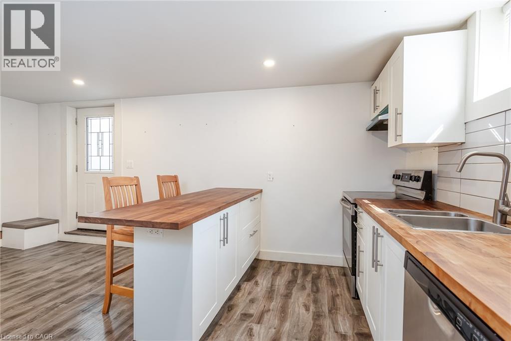 Kitchenette featuring wood-finish flooring, white cabinetry, butcher block countertops, stainless steel appliances, and a white subway tile backsplash - 40 Woodland Avenue, Kitchener, ON