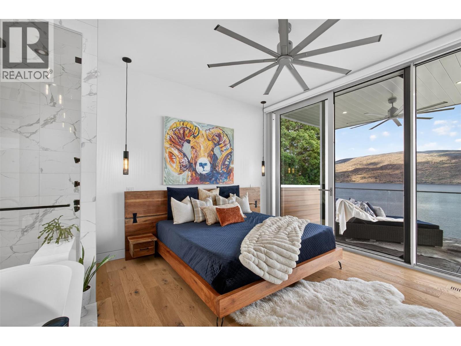Floor-to-ceiling sliding glass doors open directly onto the covered upper deck. - 5835 Vicary Road, Peachland, BC