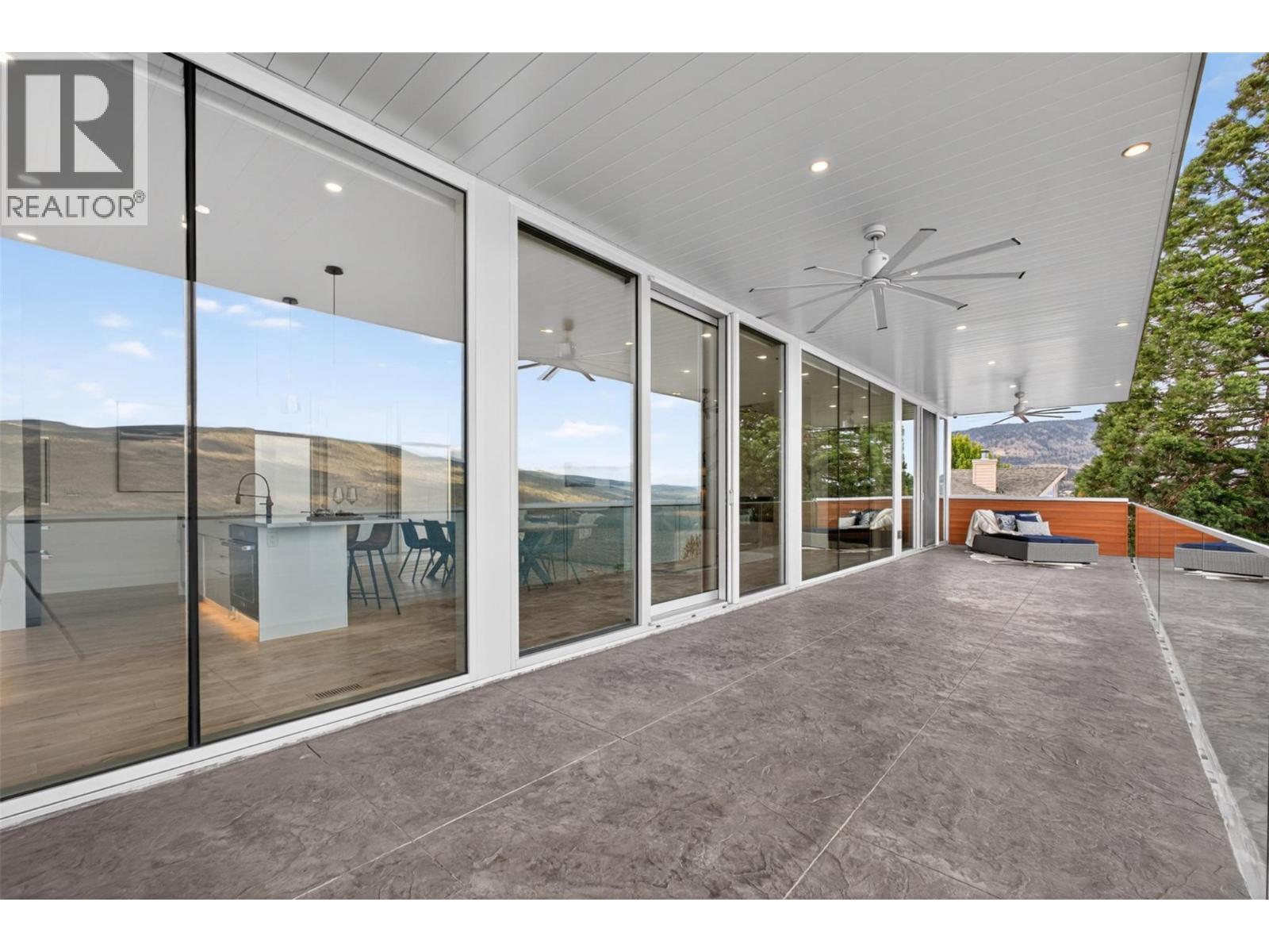 Three oversized outdoor ceiling fans provide airflow and comfort during warm summer months while maintaining the relaxed resort-style atmosphere. - 5835 Vicary Road, Peachland, BC