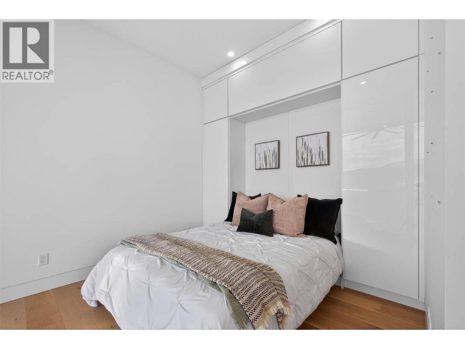 The secondary upstairs bedroom includes a built-in Murphy bed system, allowing the space to function beautifully as either a guest bedroom or a sophisticated home office. - 5835 Vicary Road, Peachland, BC