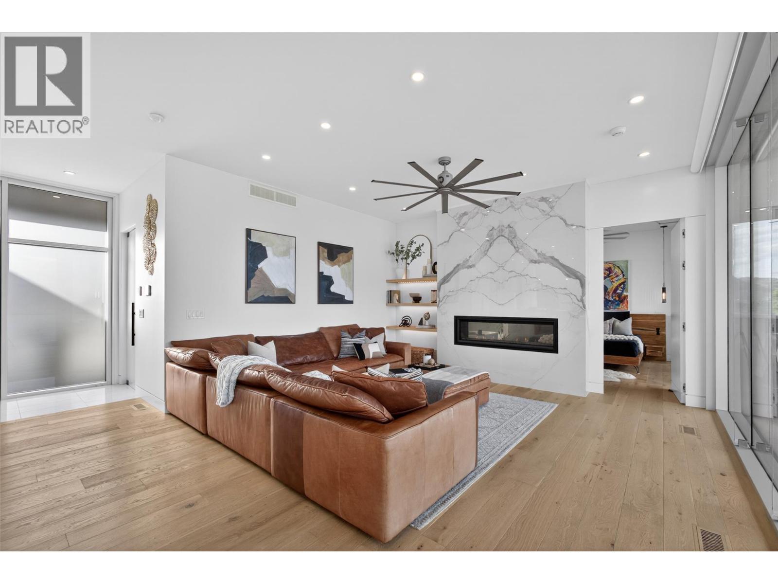 Anchoring the main living area is a spectacular oversized linear fireplace finished with massive book-matched slab tile, creating a striking architectural centrepiece. - 5835 Vicary Road, Peachland, BC
