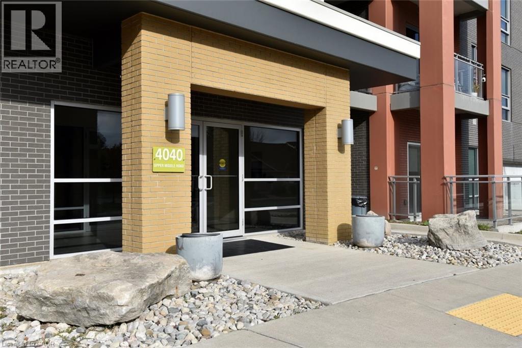 Building entrance featuring a tan brick facade and dark gray brick accents - 4040 Upper Middle Road Unit# 105, Burlington, ON