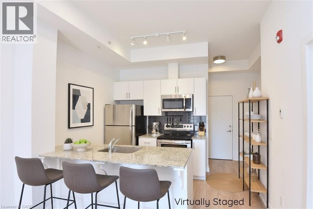 Kitchen featuring a peninsula with a built-in sink, light-toned countertop, and white cabinetry - 4040 Upper Middle Road Unit# 105, Burlington, ON
