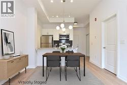 Open-concept living area with light wood-finish flooring, a contemporary chandelier, recessed lighting, and a kitchen featuring stainless steel appliances and white cabinetry -