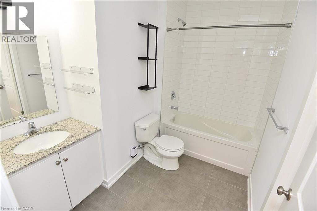 Contemporary bathroom featuring a white vanity with a light granite countertop, an oval undermount sink, and a large wall mirror - 4040 Upper Middle Road Unit# 105, Burlington, ON