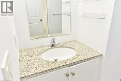 Vanity featuring a white oval sink, granite countertop, chrome faucet, white cabinetry, and brushed nickel hardware -