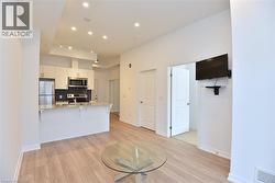 Open-concept living space featuring wood-finish flooring, recessed lighting, and a white color palette -