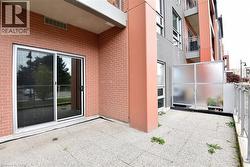 Ground-level patio featuring a sliding glass door entry, brick exterior, and a frosted privacy screen -