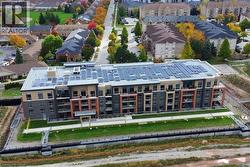 Modern multi-story building featuring an array of rooftop solar panels, multiple private balconies with glass railings, and a contemporary façade with varied exterior finishes -