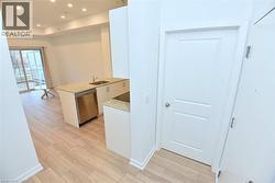 Open-concept living space with light wood-finish flooring, recessed ceiling lighting, and a kitchen island featuring a stainless steel dishwasher, undermount sink, and stone-finish countertops -