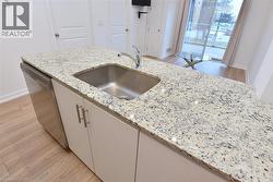 Kitchen island featuring a stainless steel undermount sink, a chrome faucet, and integrated stainless steel dishwasher -