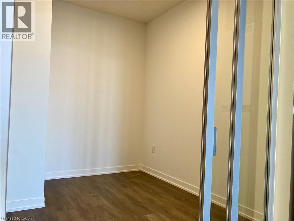 Interior room featuring wood-finish flooring, white baseboards, and a sliding glass door with a metal frame - 4878 Powers Common Unit# C-1105, Burlington, ON
