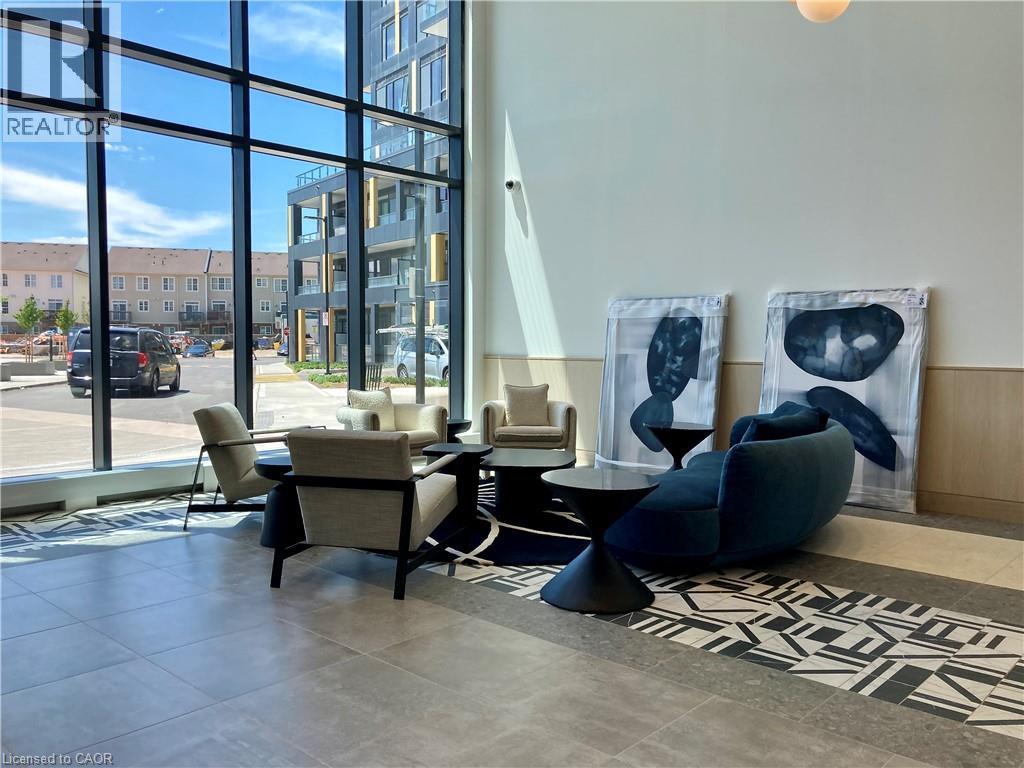 Lobby area featuring expansive floor-to-ceiling windows, modern tile flooring with a patterned inlay, and light wood-paneled walls - 4878 Powers Common Unit# C-1105, Burlington, ON