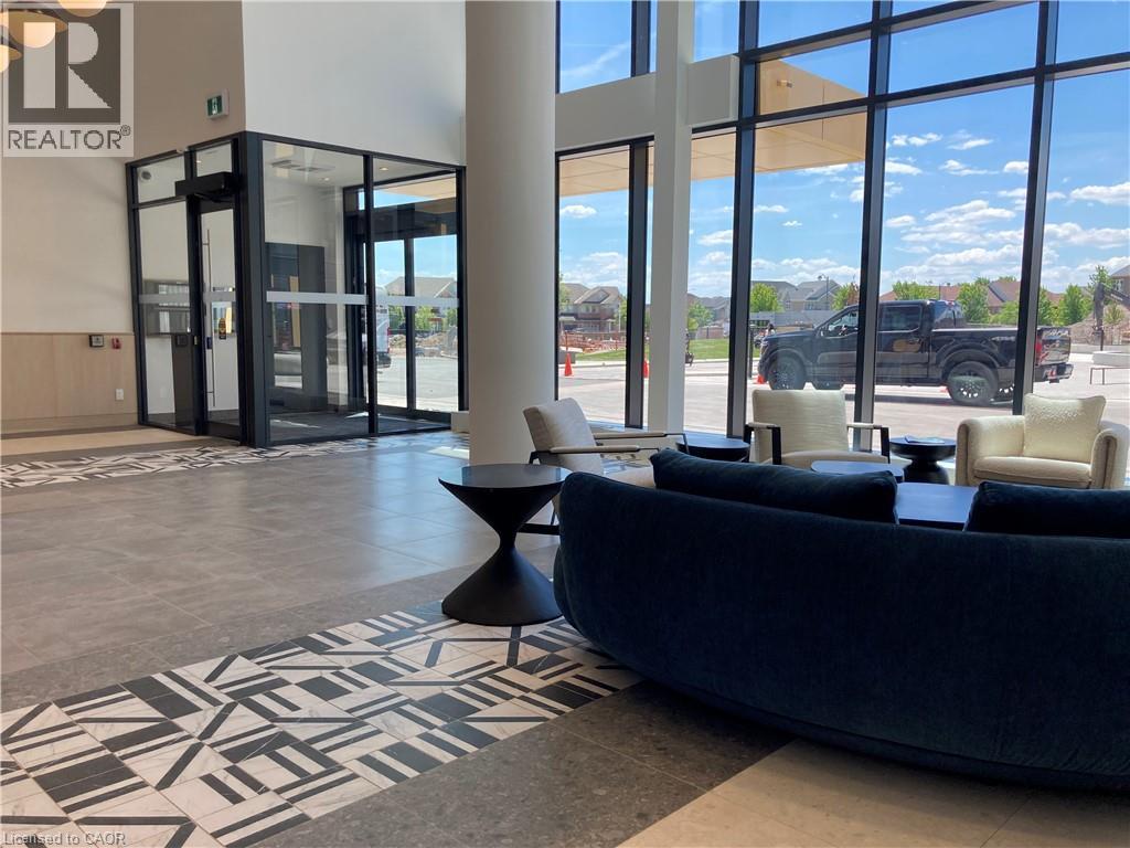 Spacious entry lobby featuring floor-to-ceiling windows, high ceilings, a revolving glass door system, and patterned floor tile accents - 4878 Powers Common Unit# C-1105, Burlington, ON