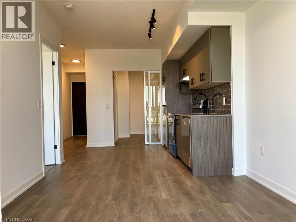 Open-concept living space featuring wood-finish flooring and a contemporary kitchen - 4878 Powers Common Unit# C-1105, Burlington, ON
