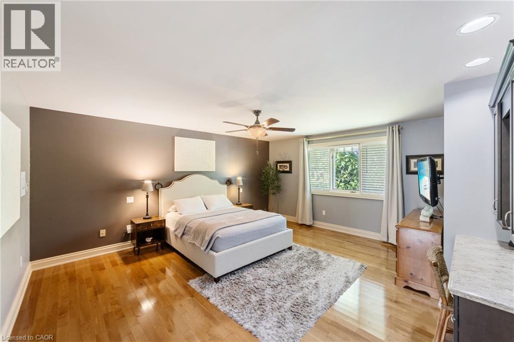 Spacious primary bedroom featuring wood-finish flooring, a ceiling fan, recessed lighting, and a large window with blinds - 7775 St. Augustine Crescent, Niagara Falls, ON