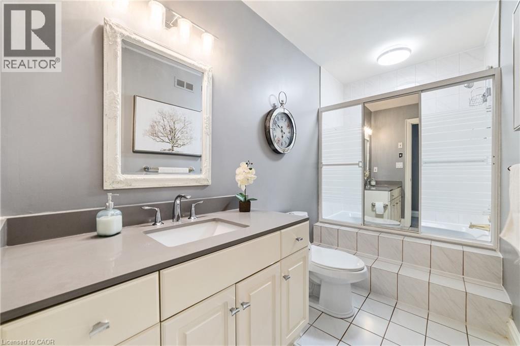 Bathroom featuring a neutral palette, a white vanity with a light gray countertop, an integrated sink with a chrome faucet, and a large mirror with an ornate white frame - 7775 St. Augustine Crescent, Niagara Falls, ON