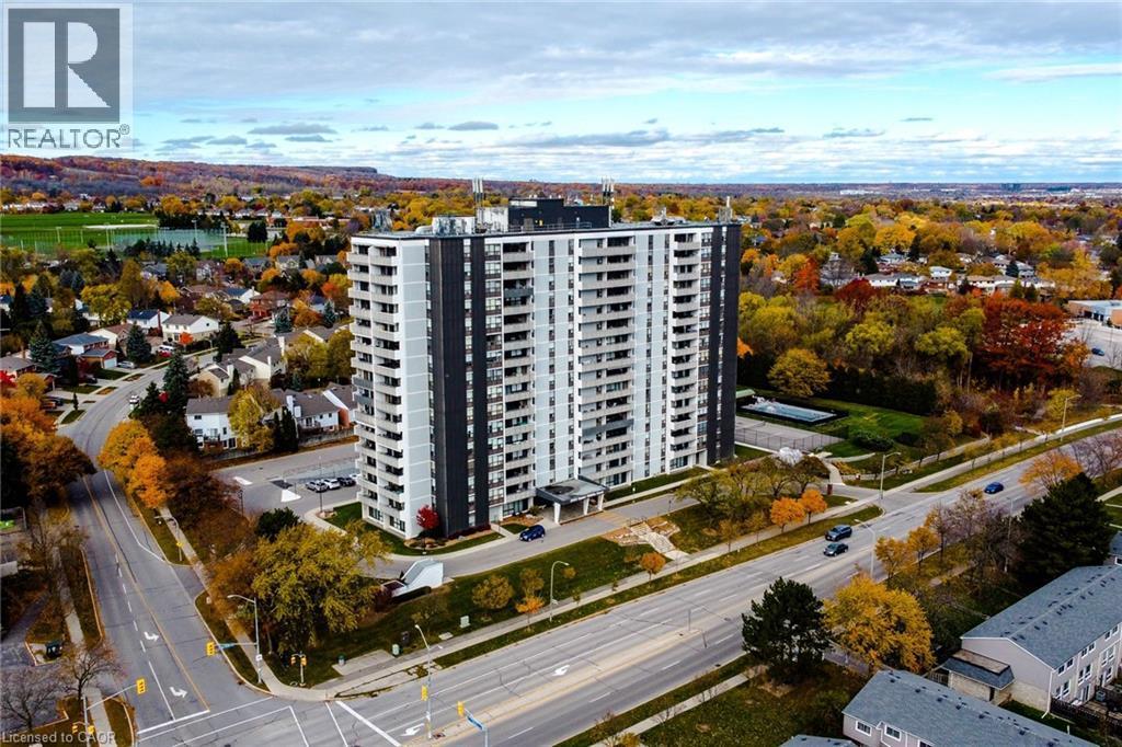 High-rise residential building featuring a two-tone facade, private balconies, and a surface parking lot - 2055 Upper Middle Road Unit# 602, Burlington, ON