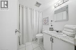 White tiled bathroom featuring a vanity with a white countertop, an undermount sink, and a framed mirror -