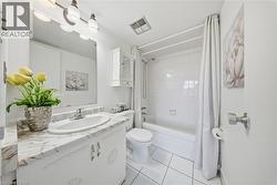 Bathroom featuring a white vanity with a marble-finish countertop, an oval undermount sink, and a three-bulb vanity light fixture -