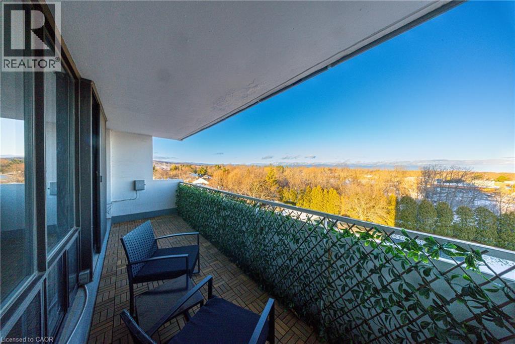 Private balcony featuring a wood-finish tile floor, full-height glass sliding doors, a decorative privacy screen, and an expansive natural landscape - 2055 Upper Middle Road Unit# 602, Burlington, ON