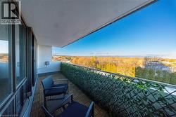Private balcony featuring a wood-finish tile floor, full-height glass sliding doors, a decorative privacy screen, and an expansive natural landscape -