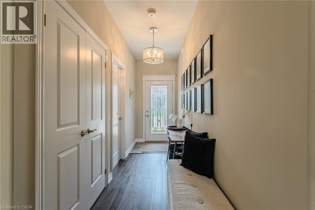 Welcoming entryway featuring dark wood-finish flooring, light tan wall paint, and white trim - 15 Winterberry Lane, Waterford, ON