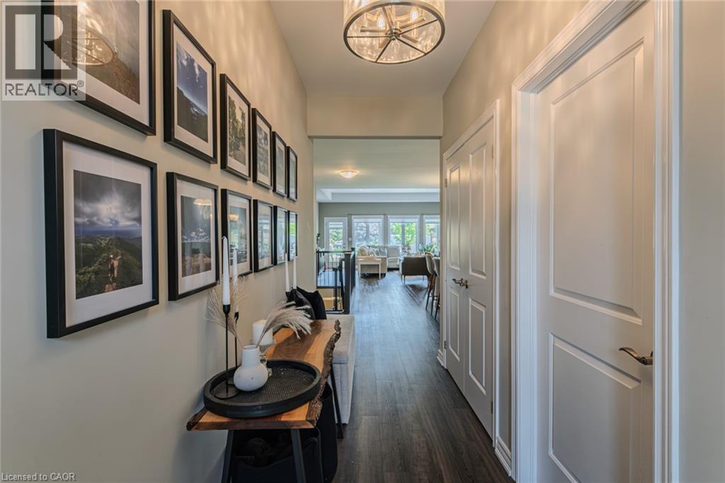 Hallway featuring wood-finish flooring and a contemporary drum pendant light fixture - 15 Winterberry Lane, Waterford, ON