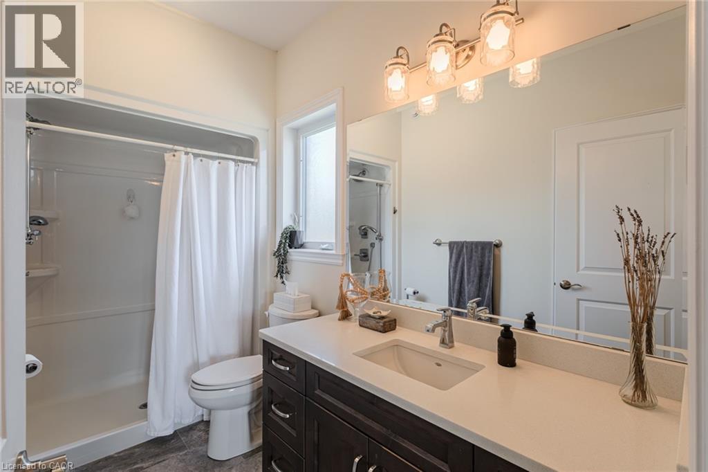 Bathroom featuring a spacious vanity with a light-toned countertop, an undermount sink, and dark wood-finish cabinetry - 15 Winterberry Lane, Waterford, ON