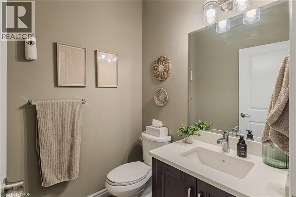 Bathroom featuring a dark wood-finish vanity with a light-toned countertop, an integrated rectangular sink, a chrome faucet, and a large wall-mounted mirror - 15 Winterberry Lane, Waterford, ON