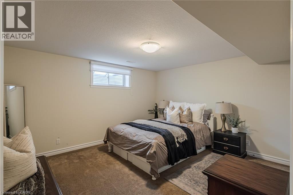 Carpeted bedroom featuring a flush mount ceiling light, an egress window with a roller shade, and neutral wall paint - 15 Winterberry Lane, Waterford, ON