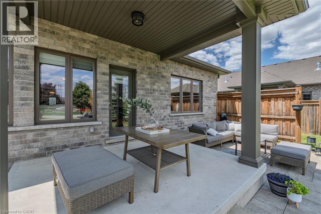 Covered outdoor patio featuring a brick exterior, concrete flooring, and a wood privacy fence - 15 Winterberry Lane, Waterford, ON
