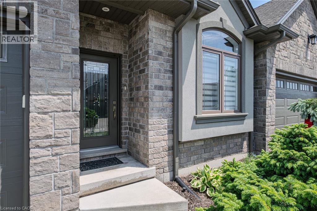 Stone and brick facade featuring a decorative glass entry door with sidelights - 15 Winterberry Lane, Waterford, ON