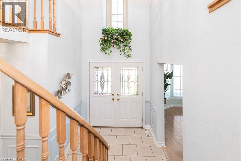 Two-story foyer featuring double entry doors with decorative glass panels, a transom window, and a tile floor - 85 Citation Crescent, Ancaster, ON
