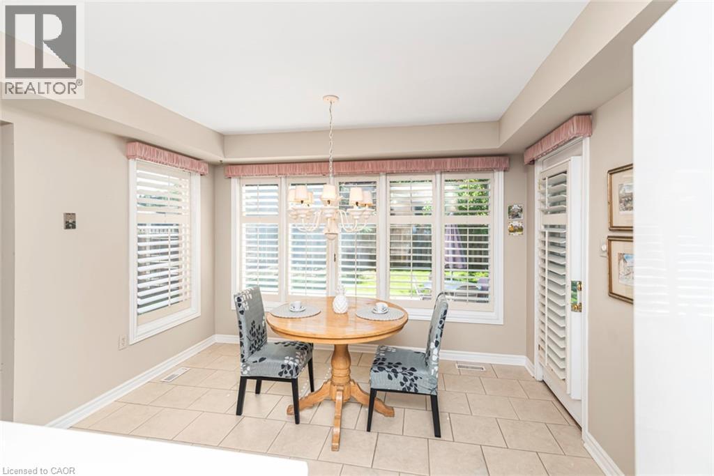 Spacious dining area with light-toned tile flooring, multiple windows featuring plantation shutters, and a chandelier lighting fixture - 85 Citation Crescent, Ancaster, ON