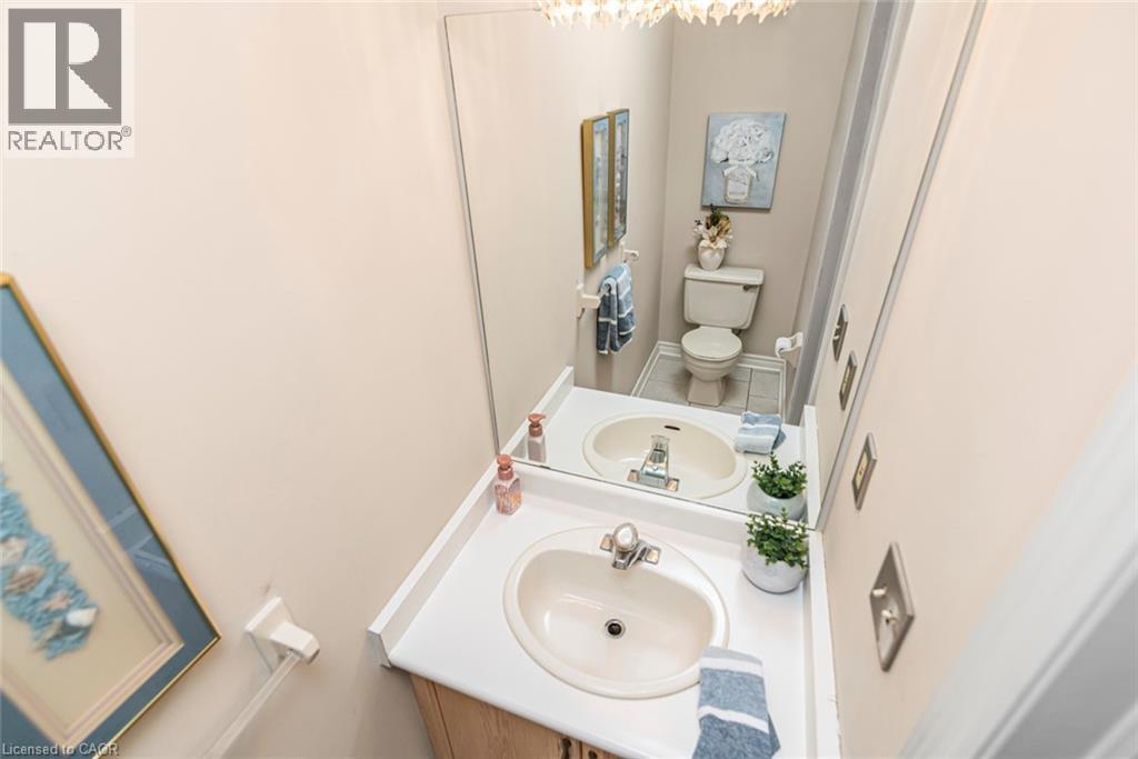 Bathroom featuring a vanity with an integrated oval sink and chrome faucet, a large wall-mounted mirror, and neutral wall tones - 85 Citation Crescent, Ancaster, ON