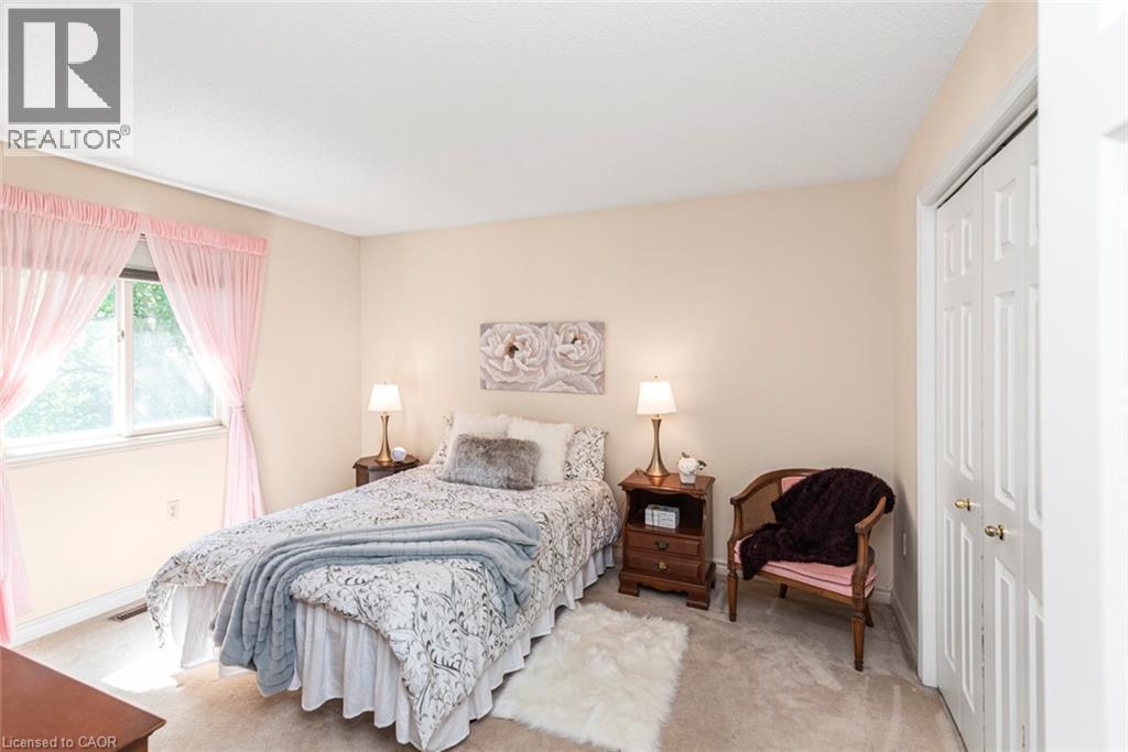 Carpeted room featuring a window with sheer pink curtains, neutral-toned walls, and a white bi-fold closet door - 85 Citation Crescent, Ancaster, ON